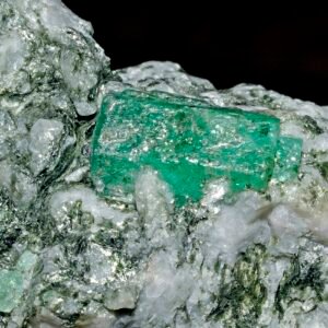 Bright green rough emerald crystal on pale matrix