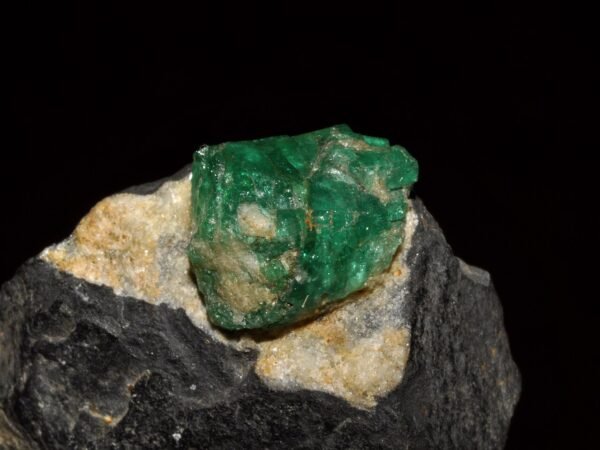 Rough emerald crystal set in dark and golden host rock