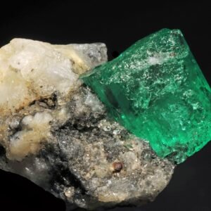 Natural emerald crystal beside pale host rock