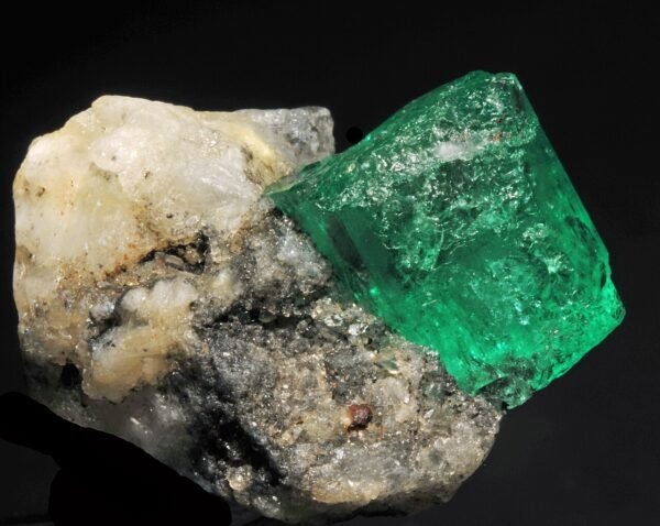 Natural emerald crystal beside pale host rock